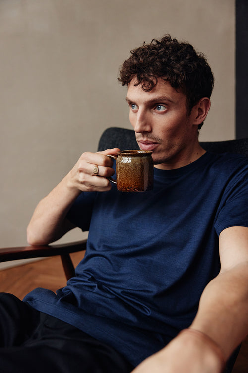 Man draagt een navy blauwe merinowollen T-shirt met ronde hals en korte mouwen van Wolk