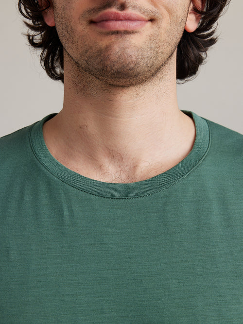 close up van man met een dennengroen merinowol T-shirt met ribgebreide kraag