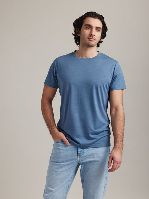 Man draagt blauw merinowol T-shirt met korte mouwen en ronde hals van Wolk