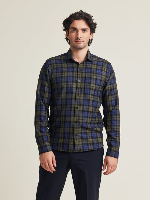 Man draagt ​​een merino wollen flanellen shirt van Wolk met blauw groen ruit patroon op een blauwe broek