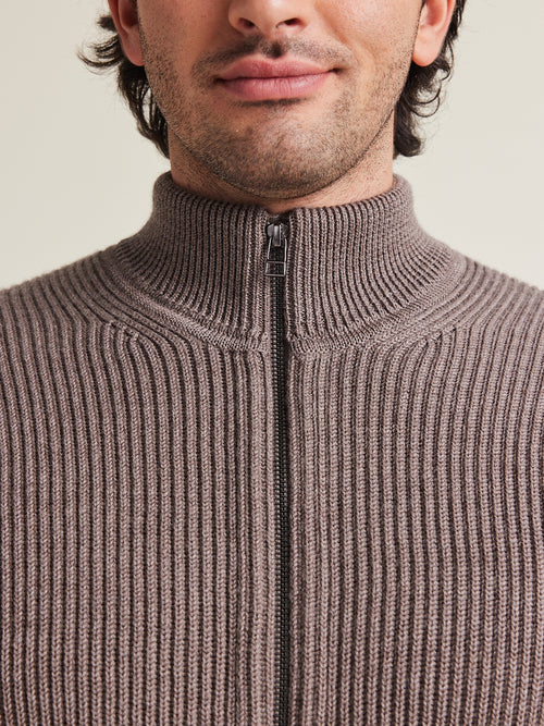 detail van merino wol vest met zip en opstaande kraag in taupe bruine kleur en cardigan brei structuur